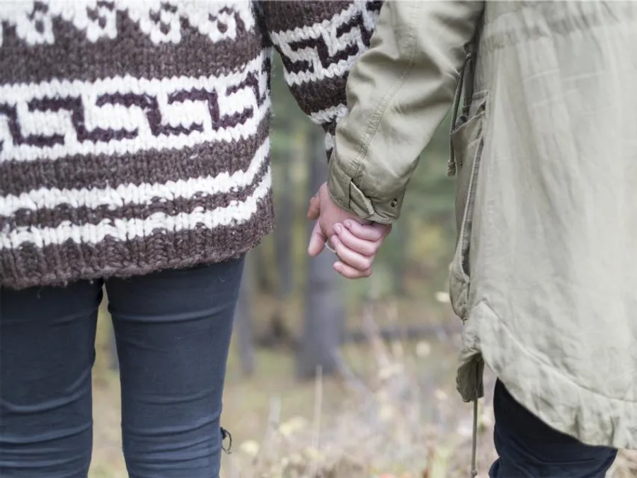 Two people standing close together, hands linked