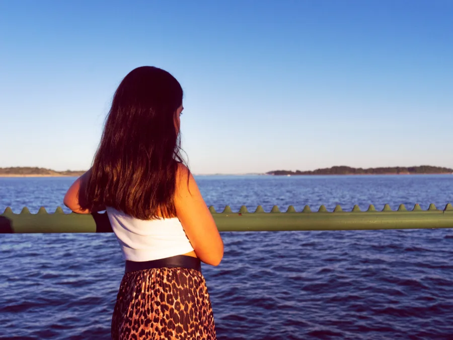 A person standing quietly, looking out over open water